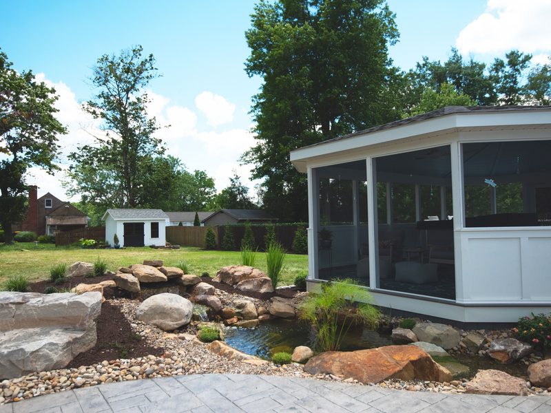 Screened backyard gazebo beside a boulder water feature
