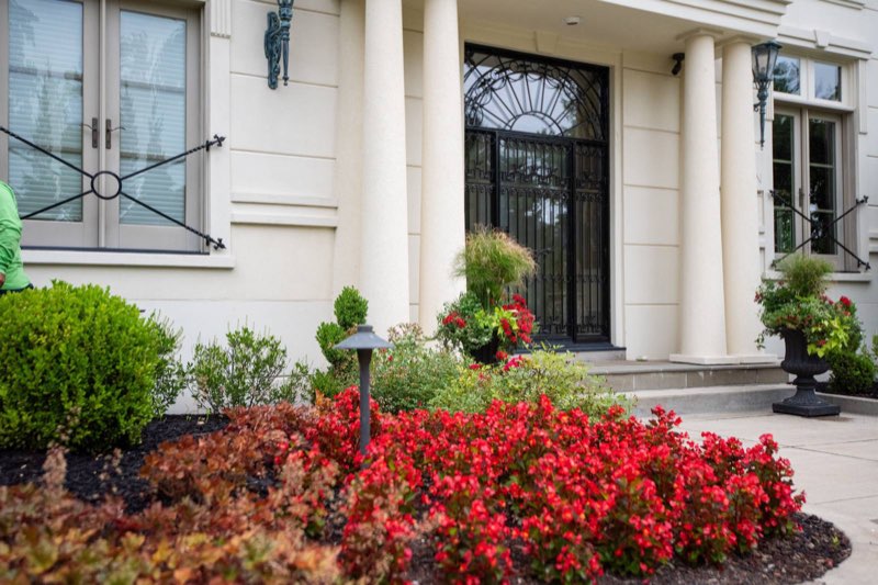 Estate front entrance with massed red begonias, boxwood, and container plantings