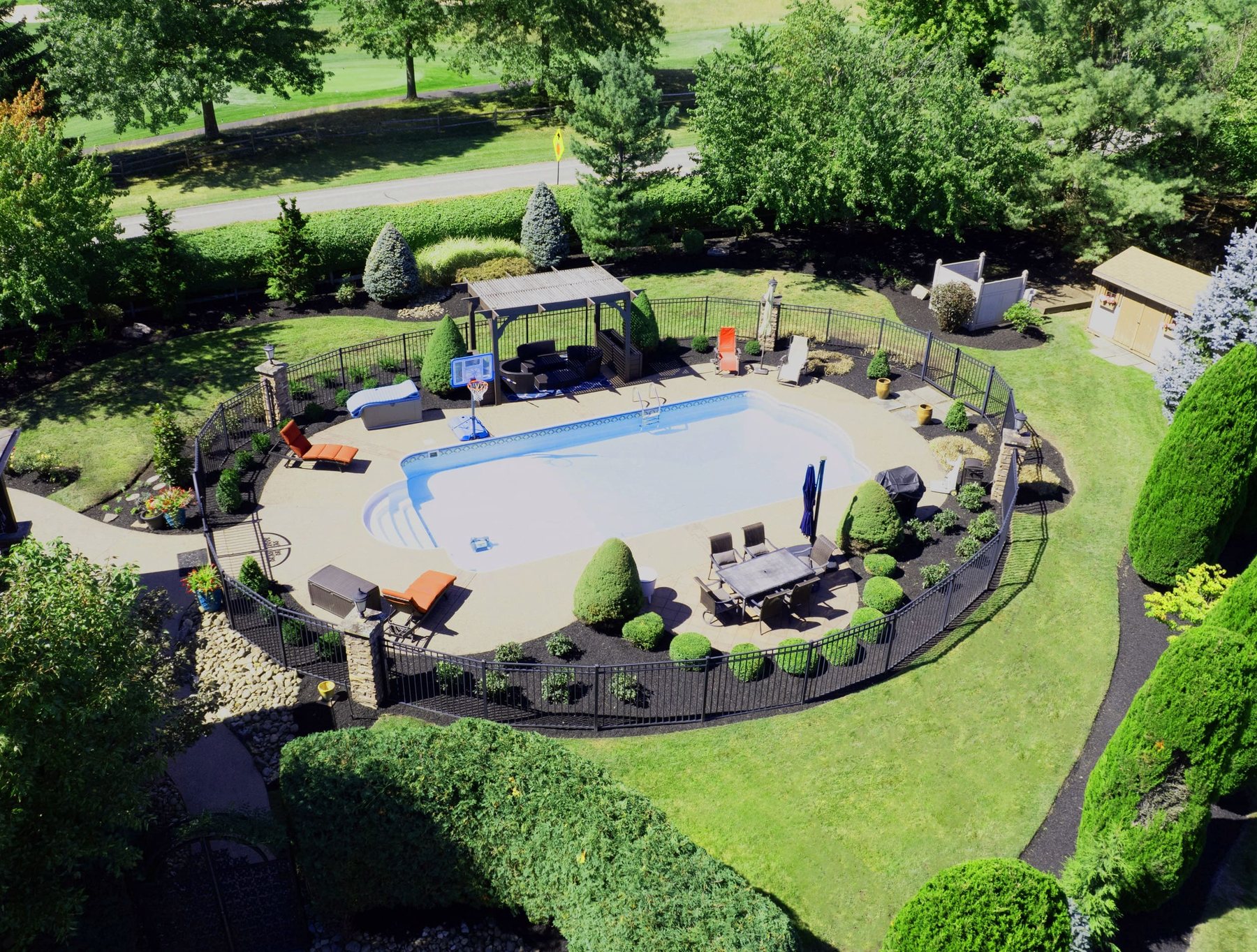 Aerial view of a backyard pool, patio and surrounding landscape beds