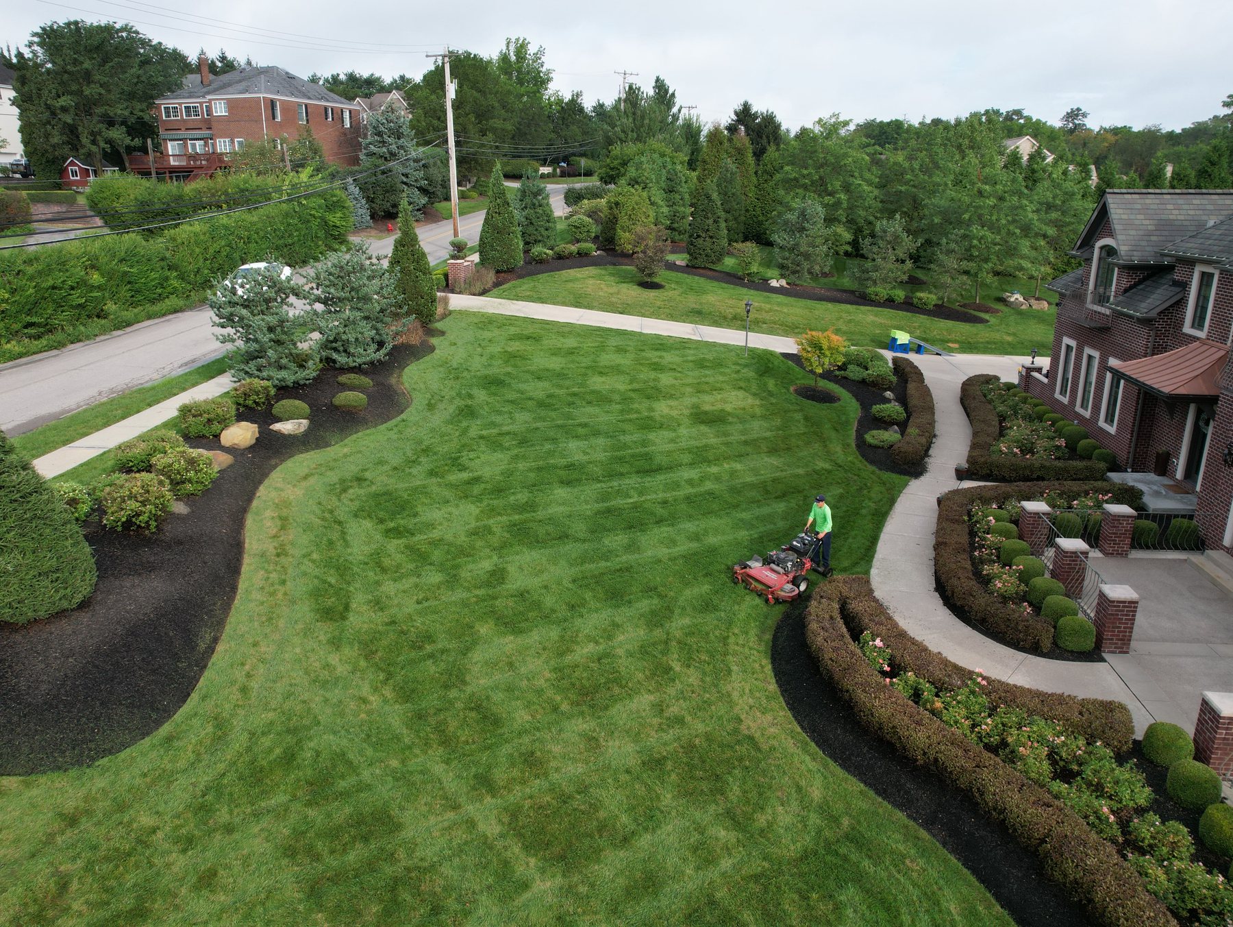 Aerial view of a freshly mowed striped lawn with curved landscape beds