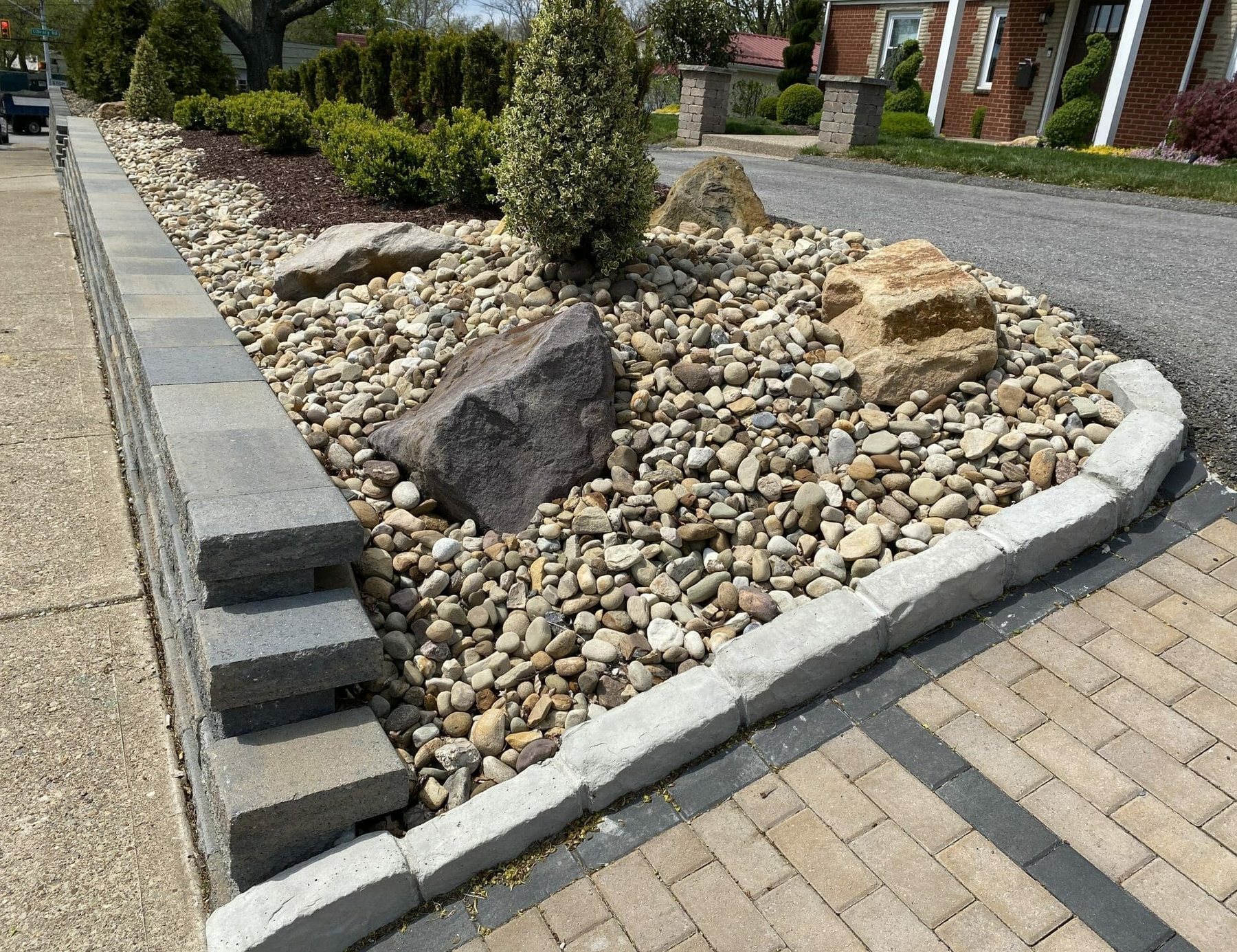 Paver walkway beside a river rock bed and segmental retaining wall
